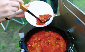 ポークビーンズダッチオーブン（鉄鍋）で豚肉を炒めたところに、野菜、豆を加える。缶詰のカットトマトを投入すれば、あとは重いフタで蒸し煮にして出来上がり。アウトドア気分が盛り上がる。