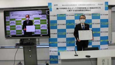 署名後に協定書を披露する酒井社長(右)