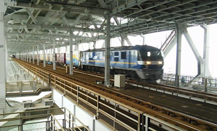 Freight train passing through the interior of a stiffening girder structure