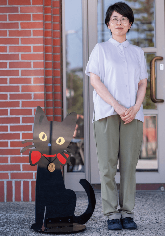 学芸員の平松さんと、水戸岡鋭治がデザインしたマスコットキャラクター「黑の助」のキャラクター看板